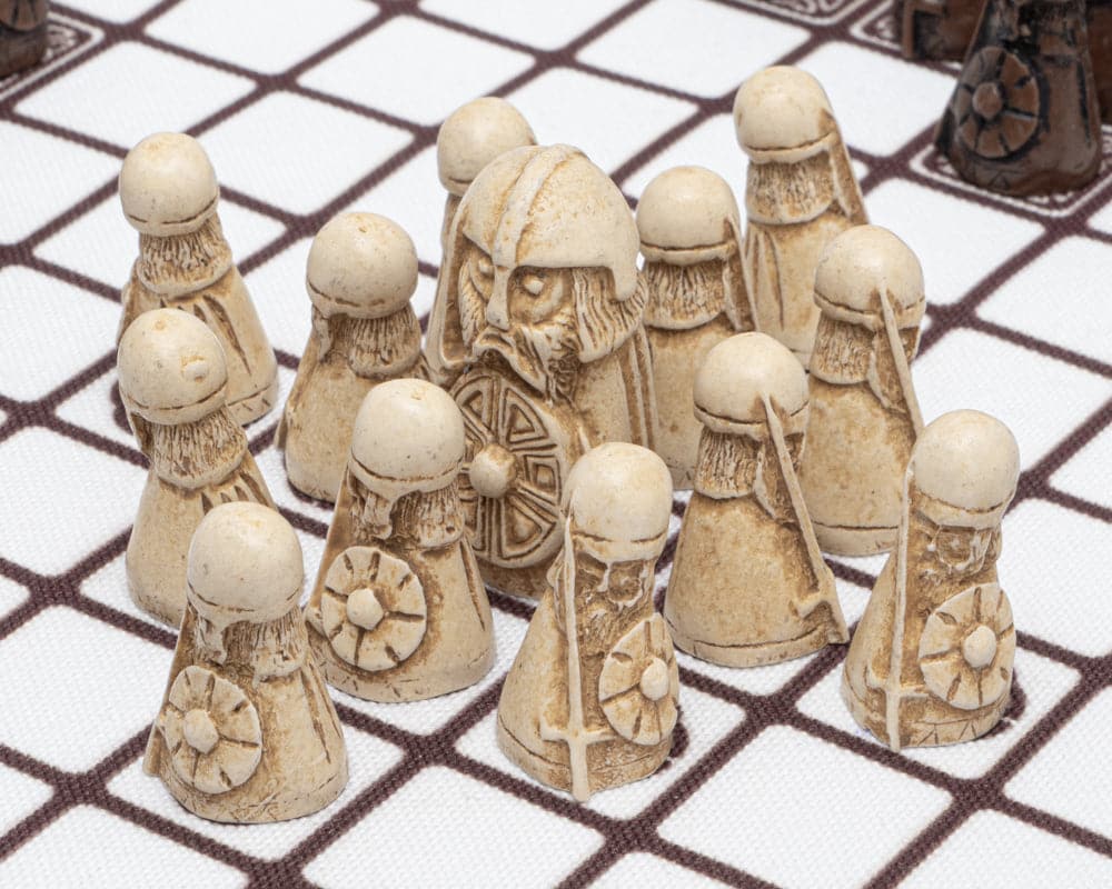 Pieces on a Hnefatafl board, featuring a white King and his 12 white Defenders.